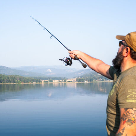 Man casting fishing line into Waitts Lake on a quiet summer morning